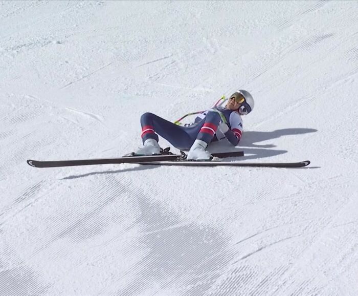Olympian skier lying on snow after a fall during competition, related to medals breaking investigation ordered from TEMU.