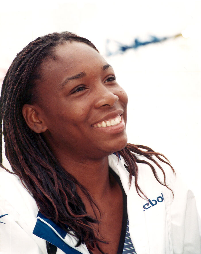 Smiling female celebrity with braided hair wearing a white jacket, representing celebrities falsely accused of horrible crimes.