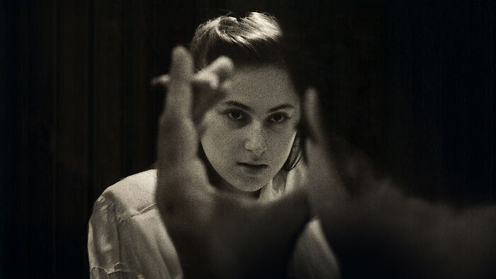 Woman with intense expression smoking a cigarette in a dark room, related to what to watch on Netflix this weekend.