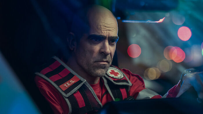 Man in a red emergency responder uniform inside a vehicle, representing what to watch on Netflix this weekend releases.