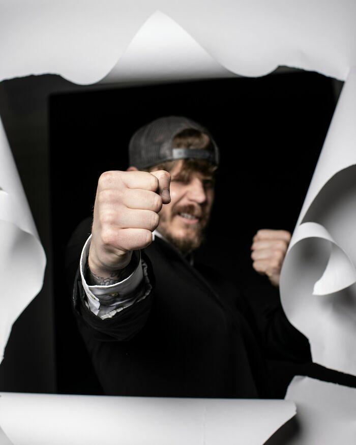 Man in cap punching through torn paper, illustrating shocking stories of friendships ended without starting.