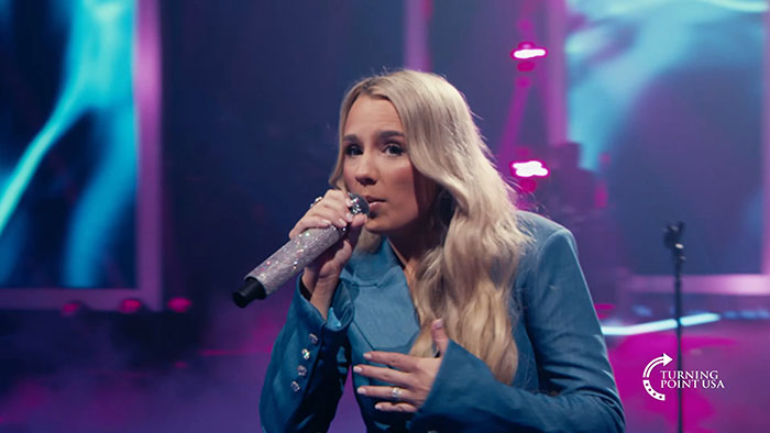 Female singer performing on stage at Kid Rock’s alternative Super Bowl show hosted by Turning Point USA event.