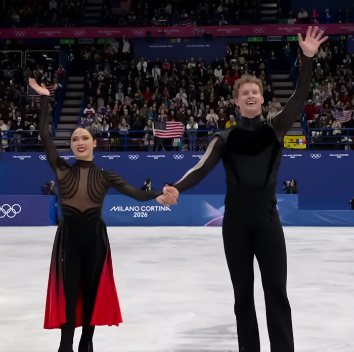 French skater and partner holding hands, waving to crowd on the ice during Olympics after suspicious win and cheating scandal.