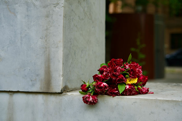 A bouquet of red and yellow flowers placed on a marble surface at an archaeological job site with possible traps nearby.