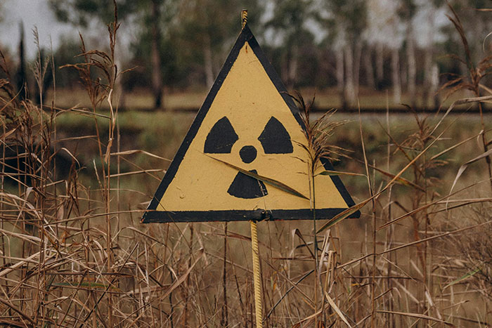 Radiation warning sign in a grassy field, illustrating potential traps at archaeologist job sites.