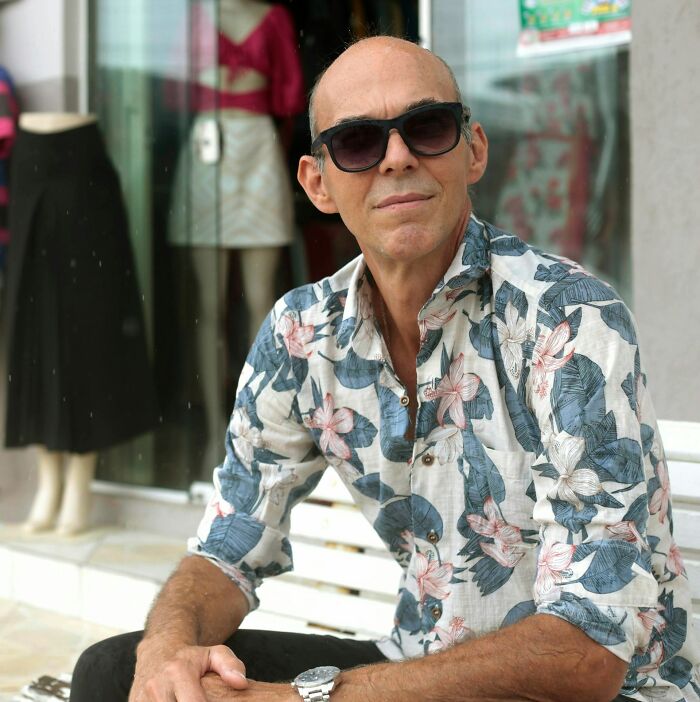 Man in floral shirt and sunglasses sitting on a bench, representing stories of friendships ended without starting.