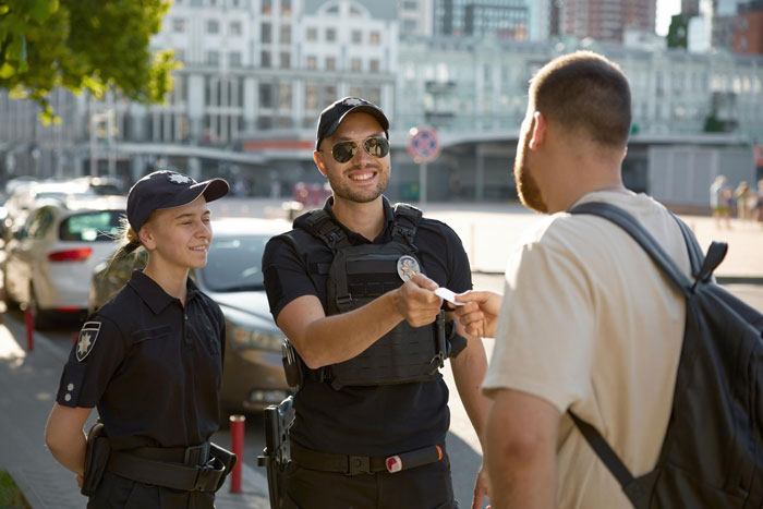 Two police officers interacting with a man outdoors, relating to a racist lady reporting dog owner to animal control.