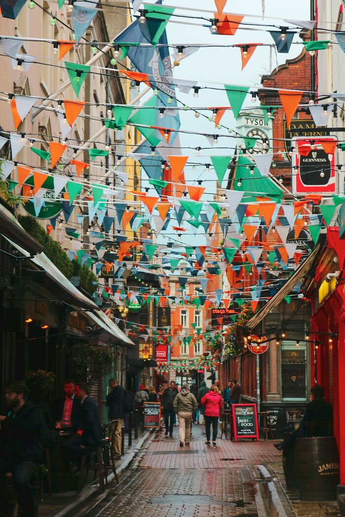 Colorful street decorations with orange, green, and white flags above a lively pedestrian area, capturing a fun mood atmosphere.