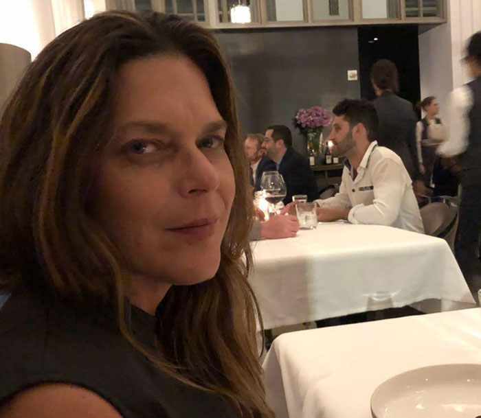 Woman with long hair seated in a restaurant, related to Savannah Guthrie, connected to missing mom investigation suspects number one and two.