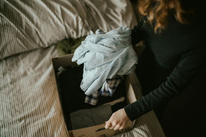 Woman packing clothes into a box symbolizing toxic ways women traumatized men in complex relationship dynamics.