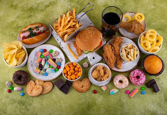 Assortment of fried foods, sugary snacks, and soda highlighting diet risks related to colon cancer breakthrough research.
