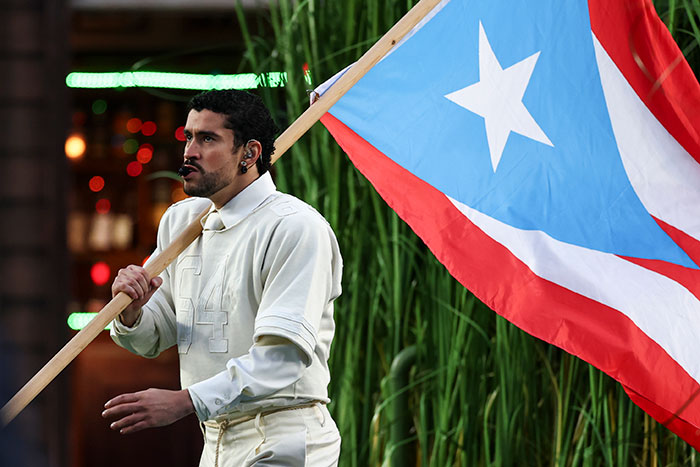 Performer holding Puerto Rican flag during a heated debate after Super Bowl fans translate Bad Bunny's explicit lyrics.
