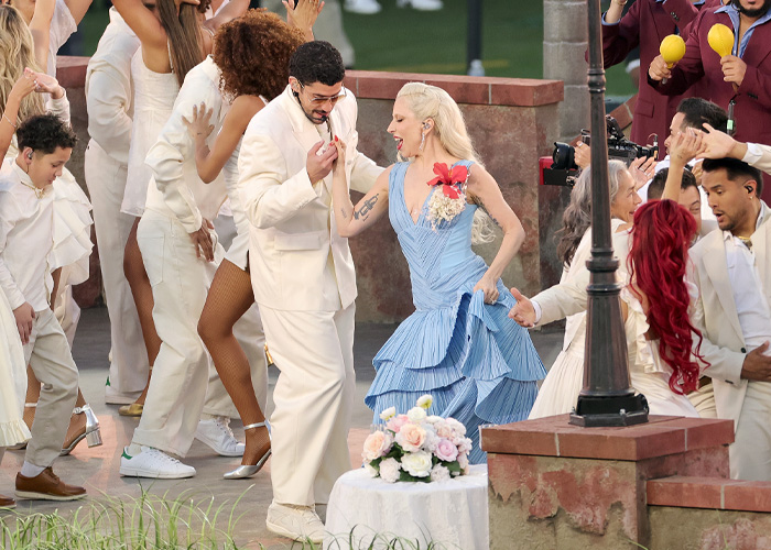 Performers dancing energetically during the Super Bowl 2026 halftime show with a lively crowd in coordinated white and blue outfits.