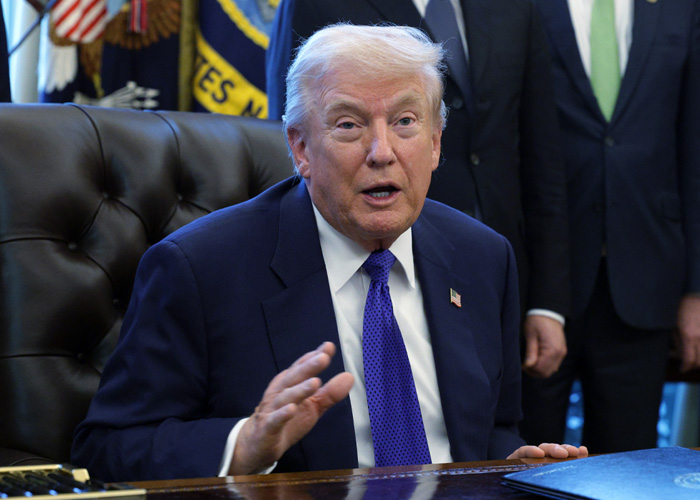 Former President Trump speaking at a desk, reacting to Bad Bunny's Super Bowl 2026 halftime show controversy.