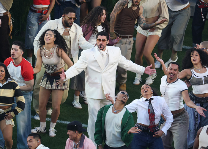 Bad Bunny performing energetically with dancers during the Super Bowl 2026 halftime show amid media attention.