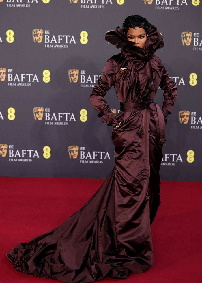 Elegant dark satin gown with dramatic collar and long train on the BAFTA red carpet, showcasing memorable BAFTA 2026 outfits.