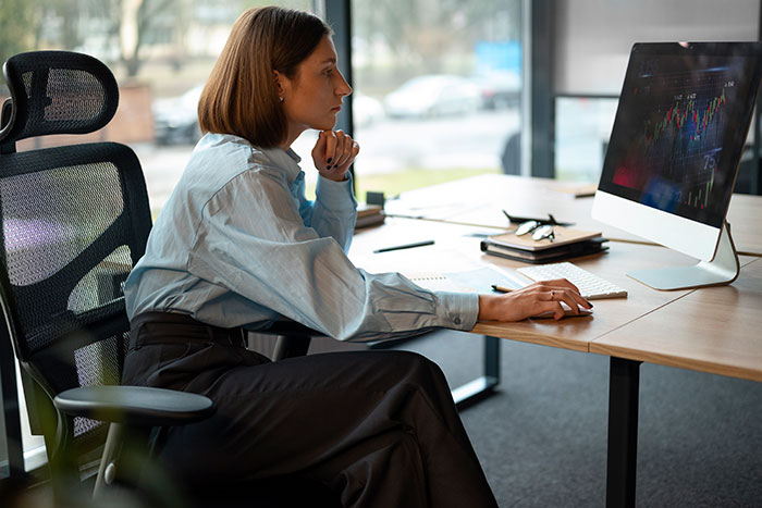 Woman sitting at desk, thoughtfully looking at computer screen, illustrating concepts of beauty standards and their impact on women. Woman sitting at desk, thoughtfully looking at computer screen, illustrating concepts of beauty standards and their impact on women.