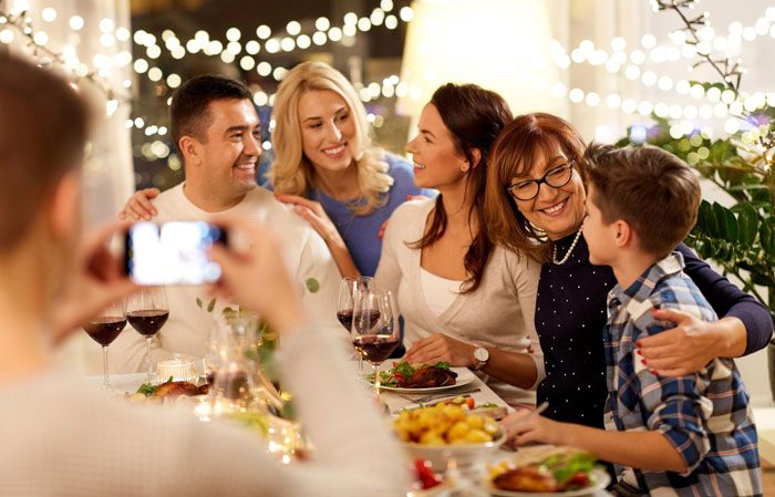 Group of family and friends at dinner party, man spinning a tale about pregnant female bestie with shocked wife nearby.