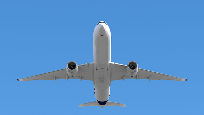 Commercial airplane flying overhead against clear blue sky, related to infamous unsolved mysteries worldwide.