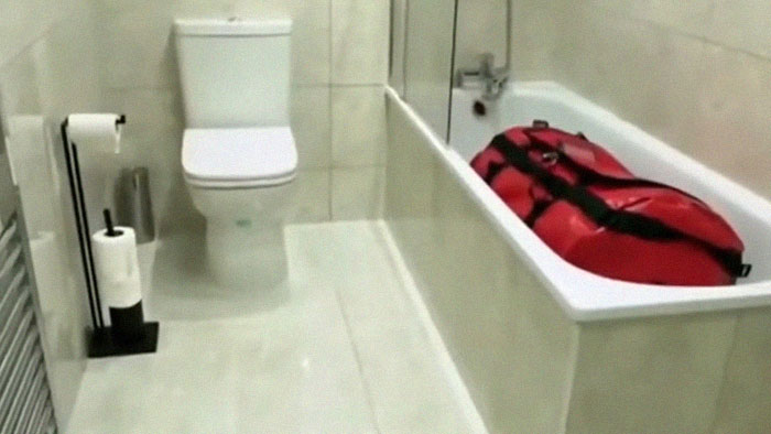 Red body bag in bathtub in a clean bathroom, evoking infamous unsolved mysteries from around the world.
