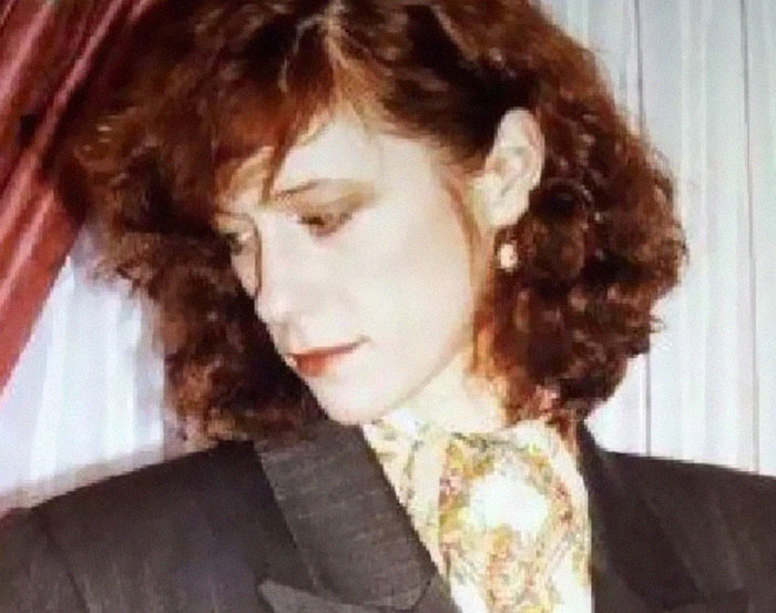 Woman with curly brown hair wearing earrings and a patterned scarf, representing infamous unsolved mysteries.