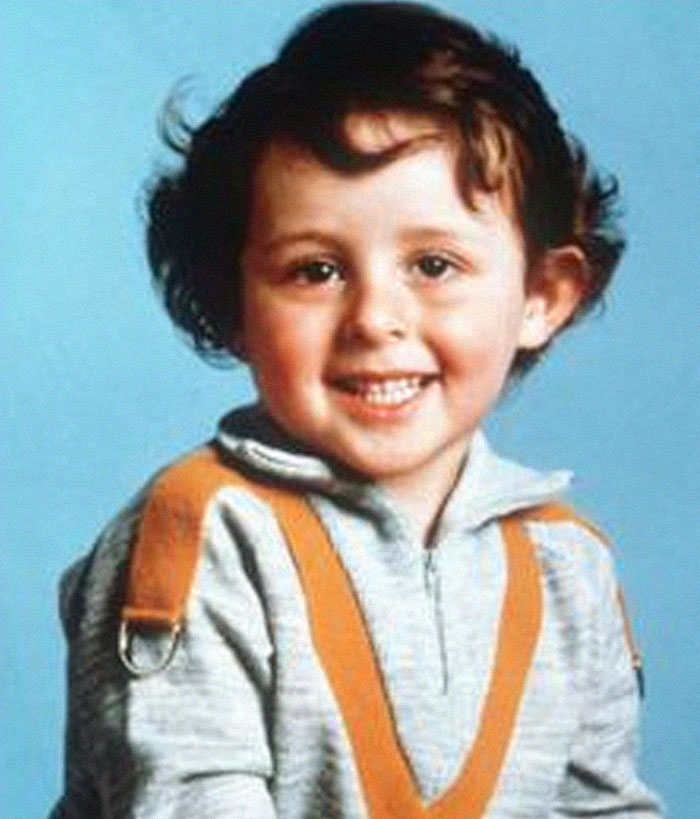Smiling young boy in a gray sweatshirt with orange suspenders, representing infamous unsolved mysteries from around the world.