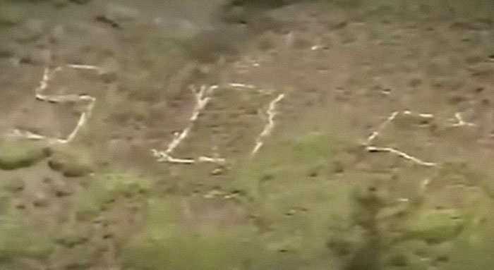 Aerial view of a mysterious giant symbol carved into a hillside, related to infamous unsolved mysteries worldwide.