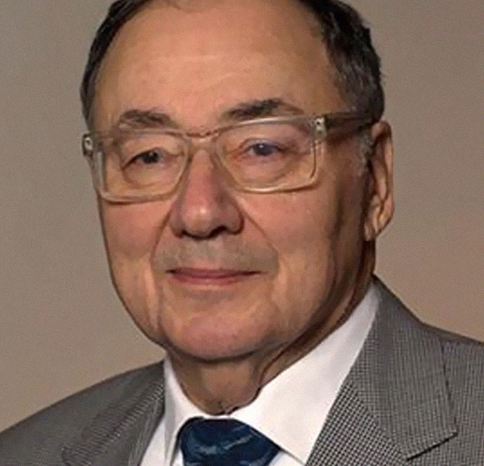 Elderly man wearing glasses and a gray suit, representing themes of infamous unsolved mysteries worldwide.