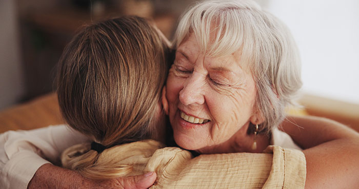 Elderly woman warmly hugging younger sister, showing comfort and support in a moment of trouble and confession.