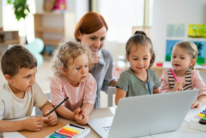 Woman with children gathered around a laptop, sharing mortified first date stories and encounters in an engaging setting.