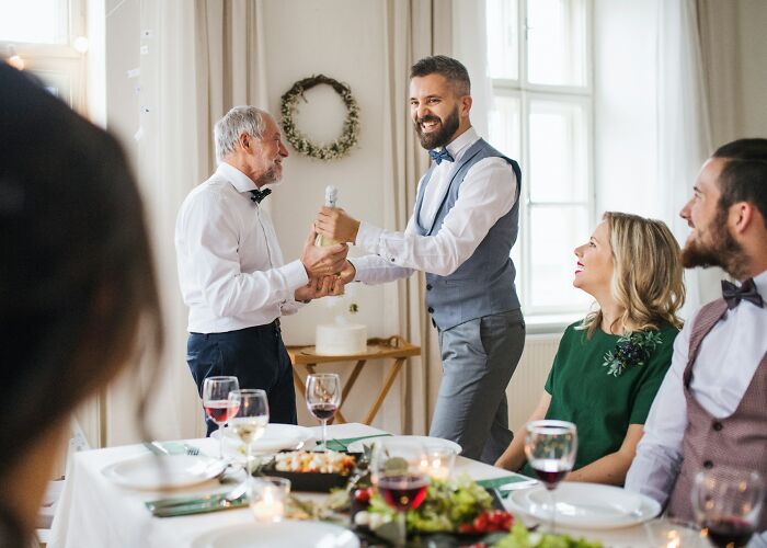 A joyful moment during a first date encounter at a dining table with wine and food in a bright room.