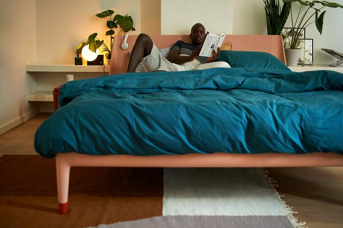 Man reading a book on a bed in a cozy modern bedroom, reflecting on audacity tales of first date encounters.