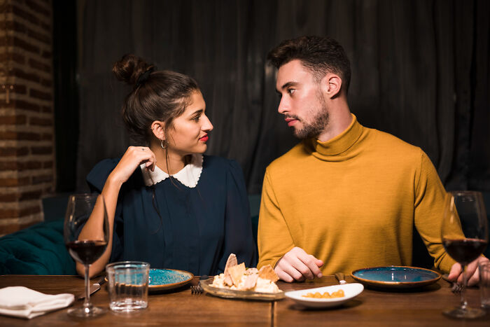 A young woman and man on a first date at a restaurant, sharing a moment amid food and drinks on the table.