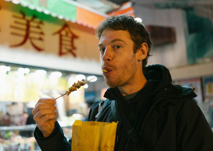 Man eating street food during a first date, capturing an awkward and mortifying encounter moment at night.