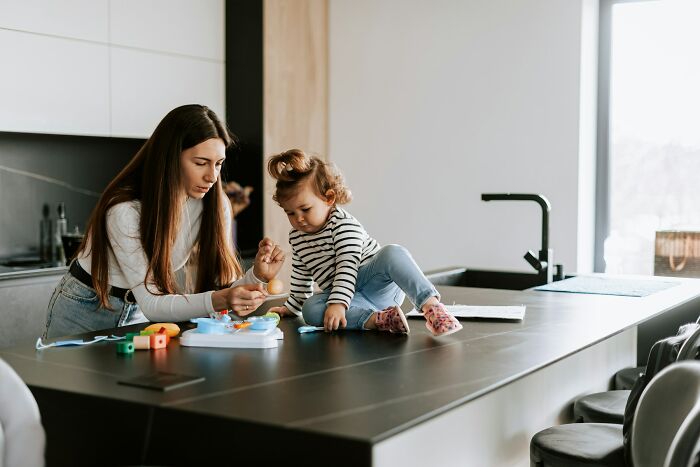 Woman and child playing on kitchen counter, sharing a moment of first date stories and mortified encounters conversation.