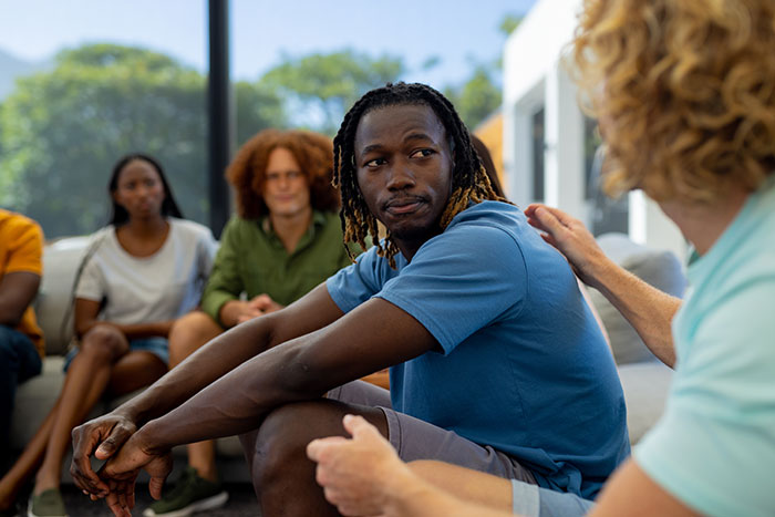A diverse group in a discussion circle, sharing stories and listening during a session on drunk confessions off the rails.