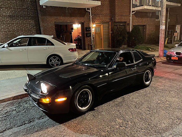 Black vintage sports car parked on a nighttime street, illustrating a theme of drunk confessions gone off the rails.