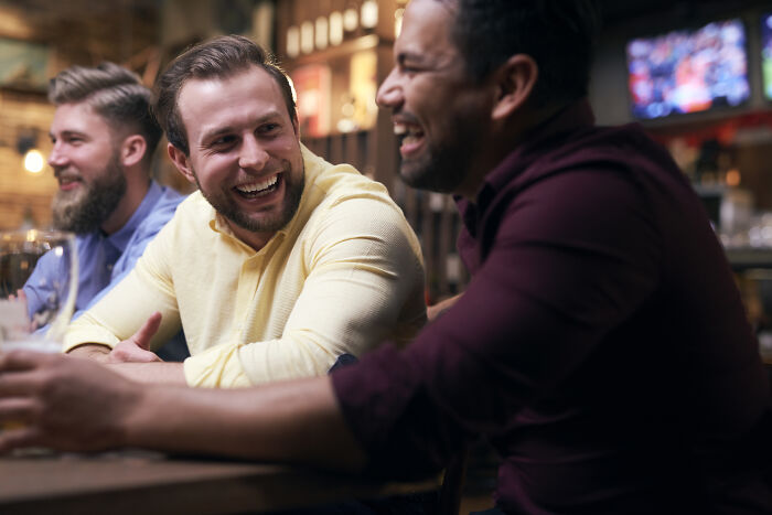 Three men laughing and sharing drunk confessions at a bar, enjoying candid moments that went off the rails.