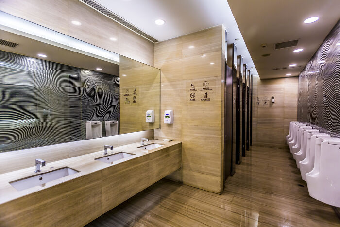 Modern public restroom with sinks and urinals, reflecting clean design and lighting, related to drunk confessions setting.