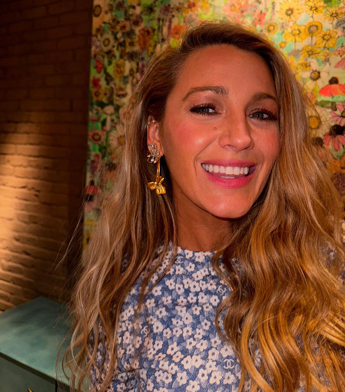 Blake Lively smiling indoors with long wavy hair and floral dress, highlighting world class privilege in a casual setting.