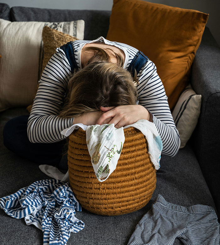 Person with head down in a basket surrounded by clothes, a weirdly hilarious image to improve your mood and feed