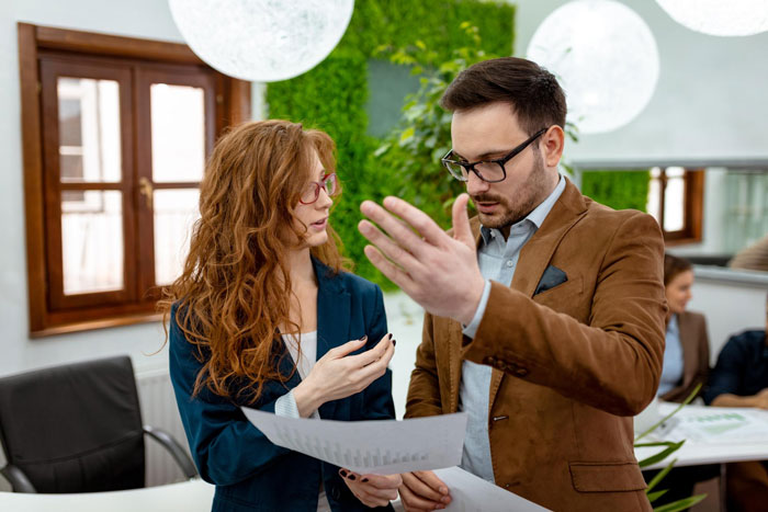 Boss and employee discussing a report in office, boss reacts surprised after calling the report basically unreadable.