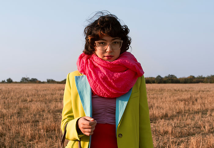 Woman in colorful style with bright pink scarf and yellow jacket, highlighting girlfriend style and childhood trauma themes.