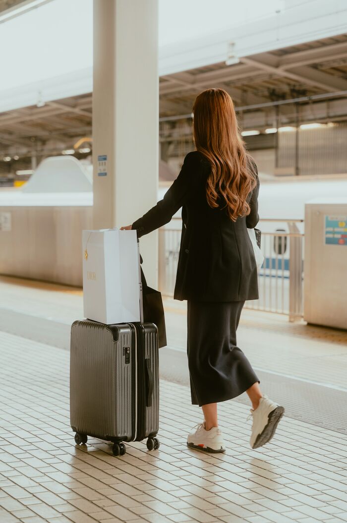 Woman at a train station with suitcase and shopping bags, illustrating themes of friendships ending without even starting.