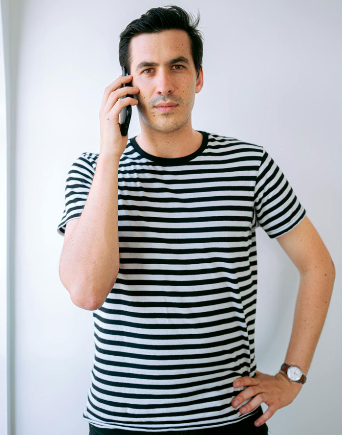 Man in striped shirt on phone with serious expression, capturing groom&rsquo;s brother bringing drama to wedding and baby shower.