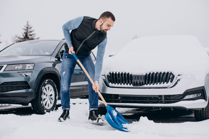 Man shoveling snow off a car, trying to secure a snow-free parking spot while frustrated at neighbor's parked vehicle. Man shoveling snow off a car, trying to secure a snow-free parking spot while frustrated at neighbor's parked vehicle.