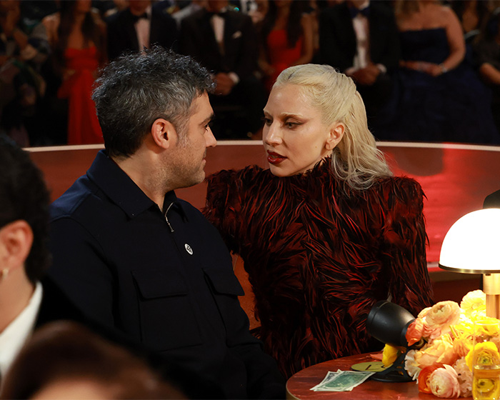 Two celebrities in conversation at the Grammys with $2 bills visible on the table amid wild theories.
