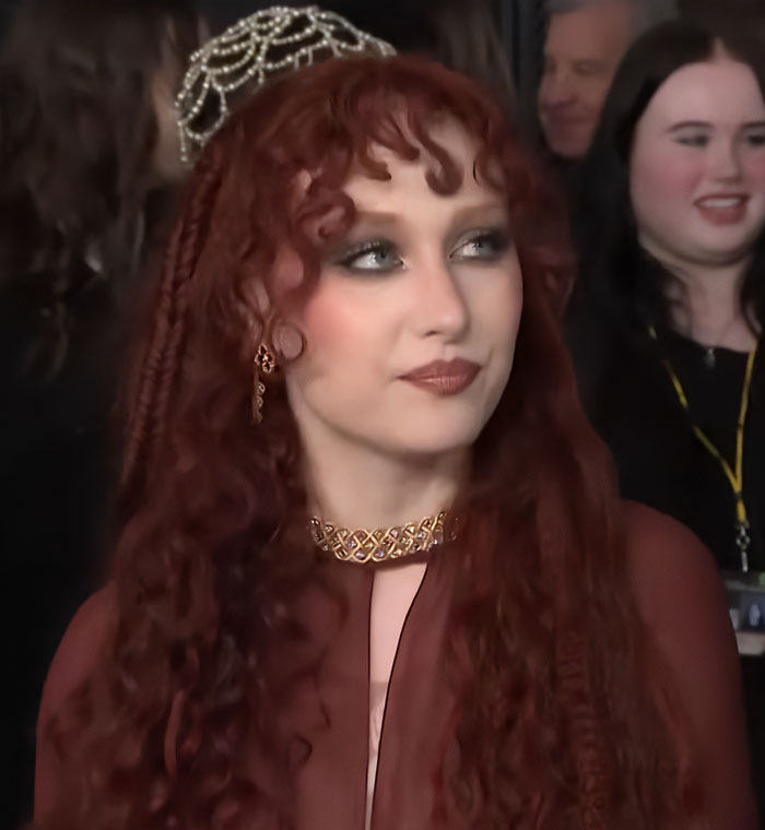 Chappell Roan with red curly hair and ornate jewelry at an event following Grammys look controversy.