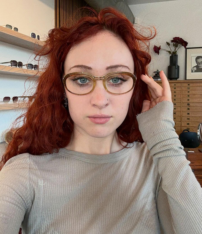 Chappell Roan with red hair and glasses posing indoors after Grammys look sparked outrage and public reaction.
