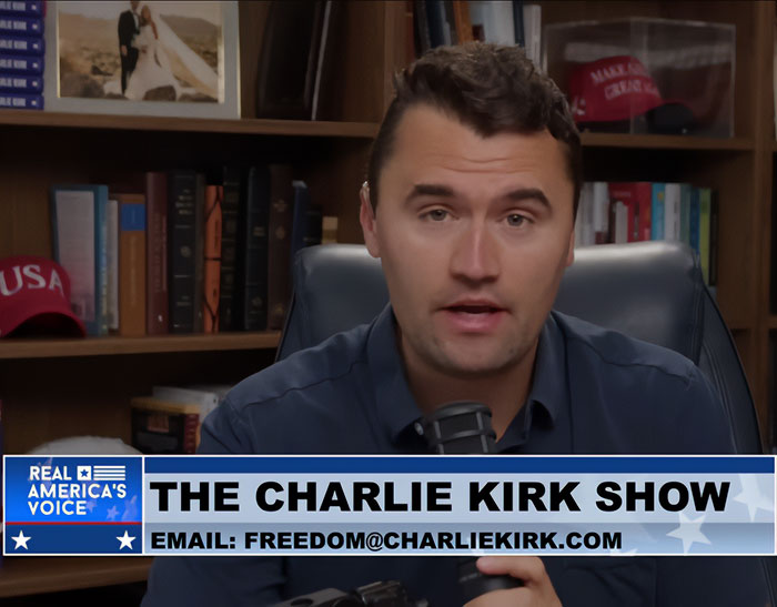 Charlie Kirk speaking on his show, with an office background, highlighting Erika Kirk's impact on his workspace.